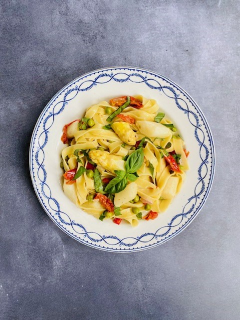 Een smaakvolle vegetarische pasta met witte asperges, doperwten, gemarineerde tomaatjes en verse basilicum. Een heerlijk vegetarisch pasta recept.